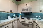 white kitchen cabinets, white microwave, white oven-range, blue tile back splash, granite counter tops